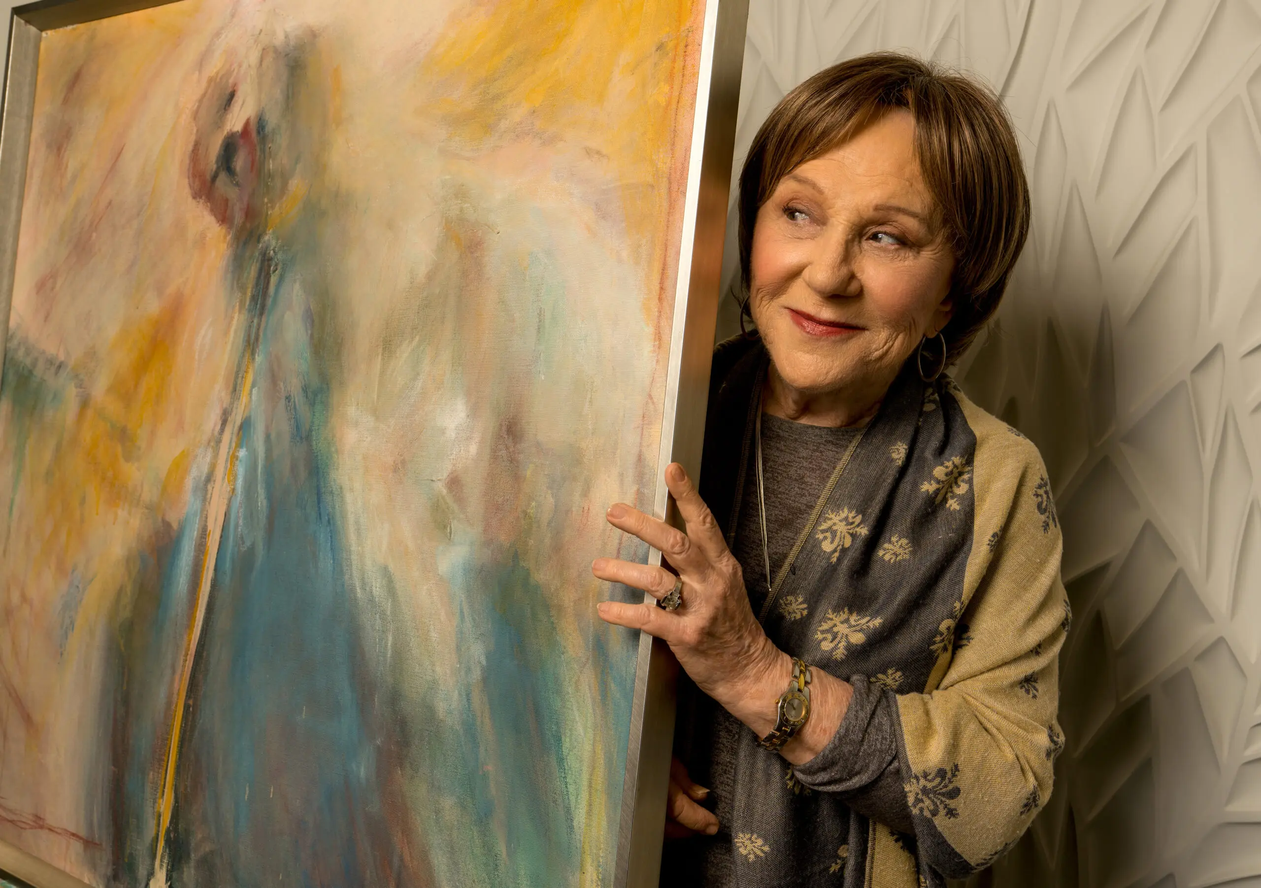 An artist holds an abstract painting.