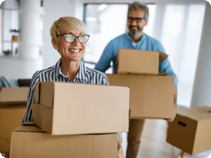 Two smiling people hold boxes.